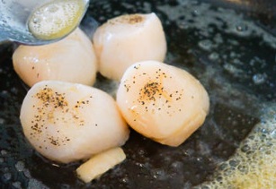鍋中放入乾貝，兩面各煎1-2分鐘，至兩面金黃，接著裝盤；煎乾貝的時候，輕輕的傾斜鍋，然後用勺子舀黃油不停的澆在乾貝上。