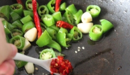 熱鍋，鍋里加入青椒、紅椒和豆瓣醬；