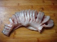 從腹部開始均勻的切條到背部，魚的兩側分別抹上鹽、料酒；