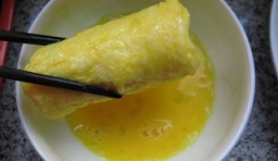 雞蛋打破在碗里打散，把卷好的香蕉放入蛋液里蘸滿蛋液；