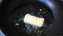 鍋里倒入植物油燒熱，把裹滿芝麻的香蕉放入油鍋里炸至金黃后撈出；