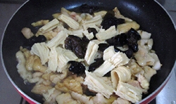 鍋中的雞肉變色后，加入料酒、醬油和少許糖翻炒均勻，再加入腐竹和木耳；