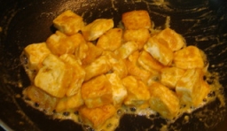 煎好的豆腐和炒香的蛋黃炒拌均勻，每塊豆腐都裹上像金粉一樣的鹹鴨蛋黃；