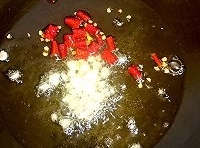 鍋中留有少許的底油，放入蒜粒和干辣椒段，炒出香味；
