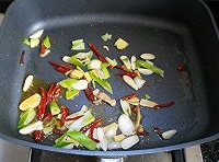 鍋中留有少許的底油，下入干辣椒、蔥段、薑片和蒜片，炒出香味；